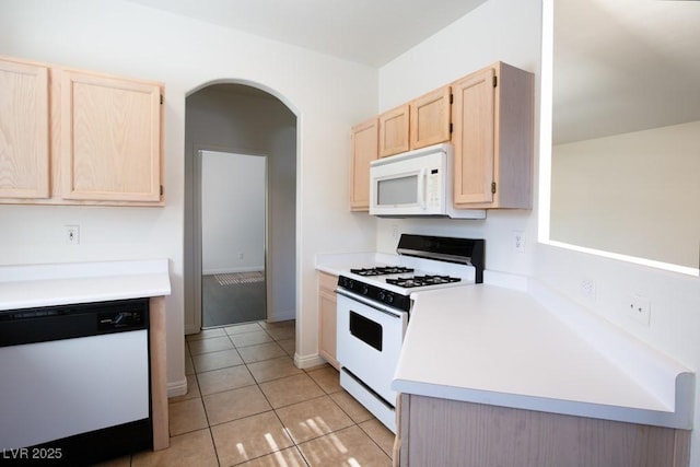 kitchen featuring light tile patterned flooring, light brown cabinetry, and white appliances