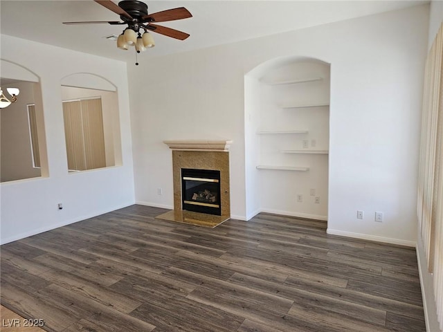 unfurnished living room with dark hardwood / wood-style flooring, a tiled fireplace, and ceiling fan with notable chandelier