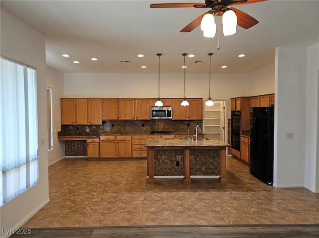 kitchen featuring sink, hanging light fixtures, stone counters, decorative backsplash, and black appliances