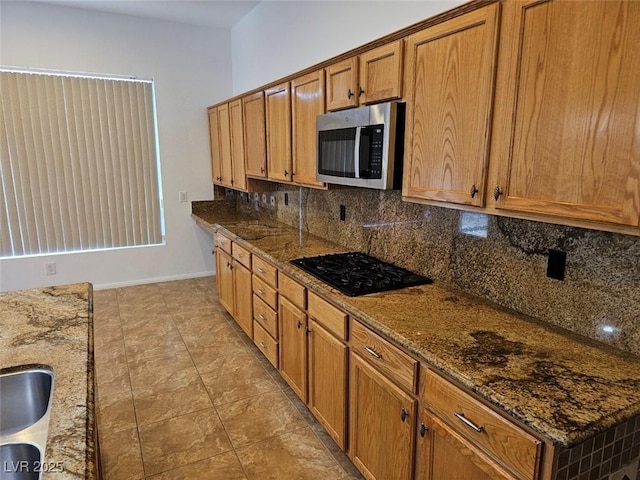 kitchen with backsplash, black gas cooktop, and dark stone counters