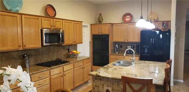 kitchen with sink, a center island with sink, pendant lighting, decorative backsplash, and black appliances