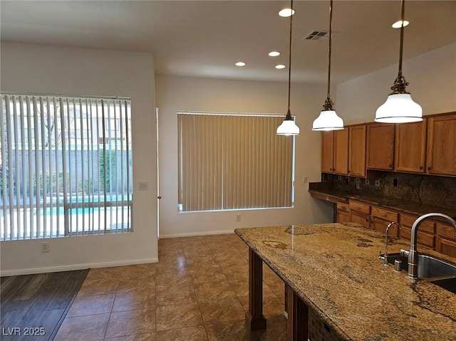 kitchen with dark stone counters, decorative light fixtures, sink, and backsplash