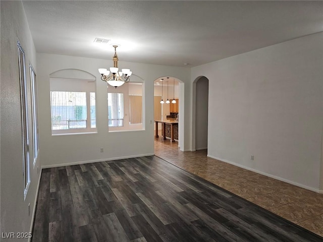 empty room with dark hardwood / wood-style flooring and a chandelier