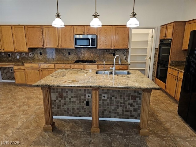 kitchen with decorative light fixtures, a kitchen island with sink, sink, and black appliances