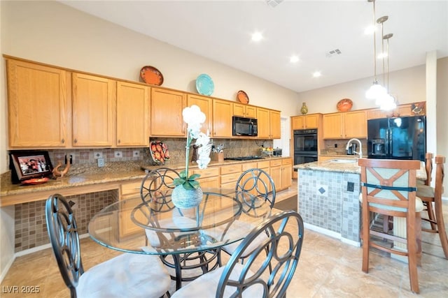 kitchen with pendant lighting, sink, light stone counters, black appliances, and decorative backsplash