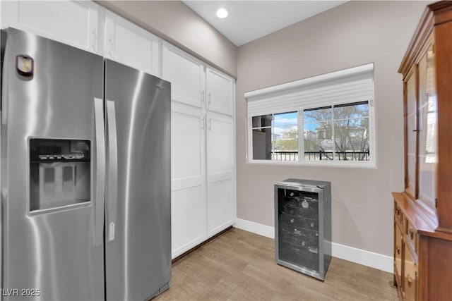 kitchen with white cabinets, stainless steel refrigerator with ice dispenser, wine cooler, and light hardwood / wood-style floors