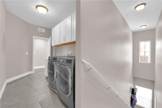 washroom with independent washer and dryer, light tile patterned floors, and cabinets