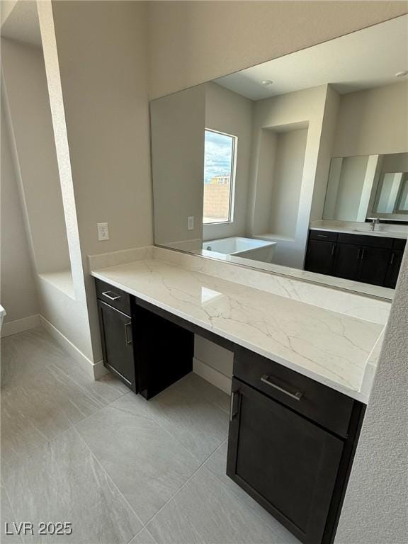4630 Blushing Dawn Ave, Las Vegas, NV 89118 - kitchen featuring light stone counters, dark cabinets, light tile patterned floors, a sink, and baseboards
