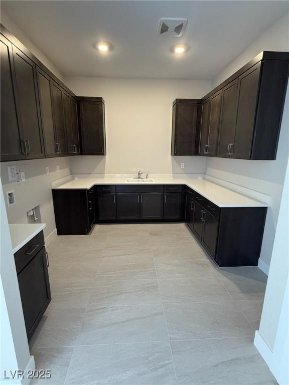 4630 Blushing Dawn Ave, Las Vegas, NV 89118 - kitchen with a sink, dark brown cabinetry, light countertops, recessed lighting, and baseboards