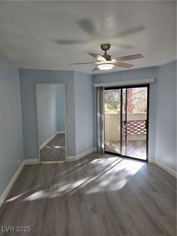 empty room with dark wood-type flooring, ceiling fan, and a textured ceiling