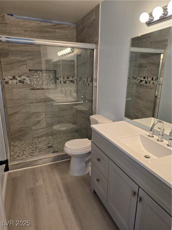 bathroom featuring walk in shower, vanity, toilet, and hardwood / wood-style floors