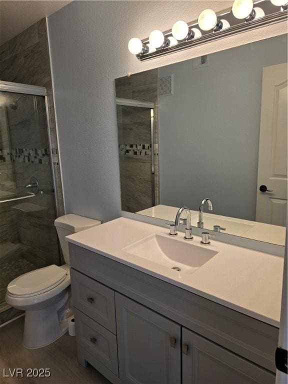 bathroom featuring vanity, wood-type flooring, a shower with door, and toilet