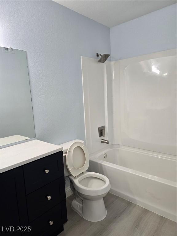 full bathroom featuring vanity, hardwood / wood-style flooring, toilet, and washtub / shower combination