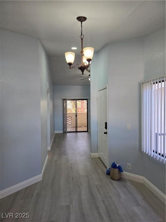 corridor with wood-type flooring and a notable chandelier