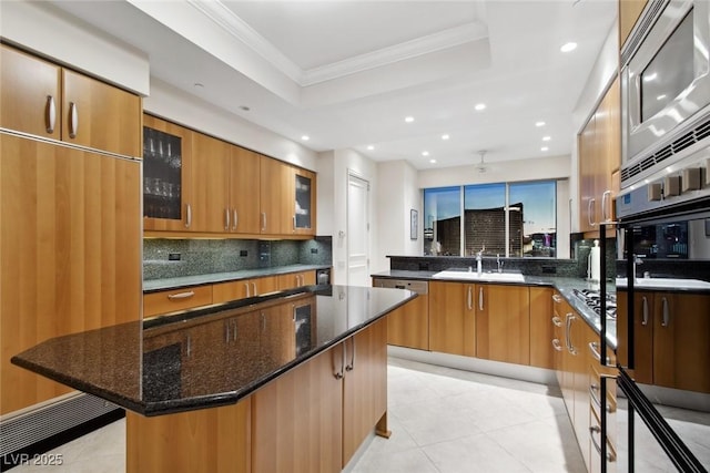 kitchen featuring a kitchen island, sink, backsplash, a kitchen breakfast bar, and a tray ceiling