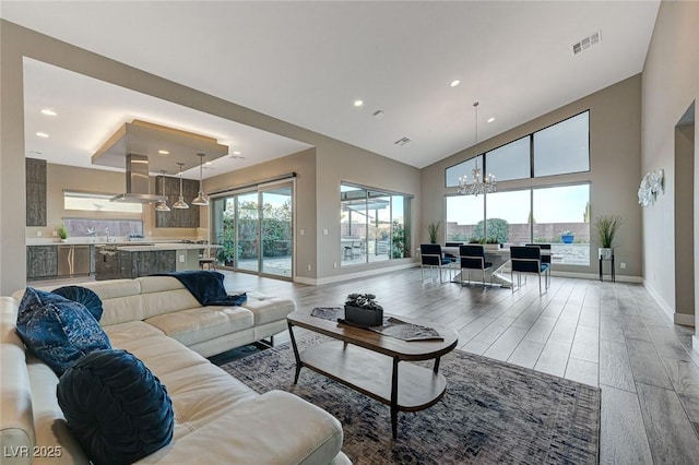 living room featuring a notable chandelier, a towering ceiling, hardwood / wood-style floors, and a wealth of natural light