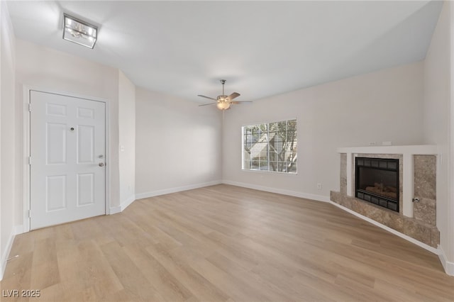 unfurnished living room with a tile fireplace, ceiling fan, and light hardwood / wood-style flooring