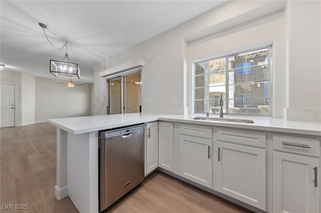 kitchen featuring sink, dishwasher, kitchen peninsula, pendant lighting, and white cabinets