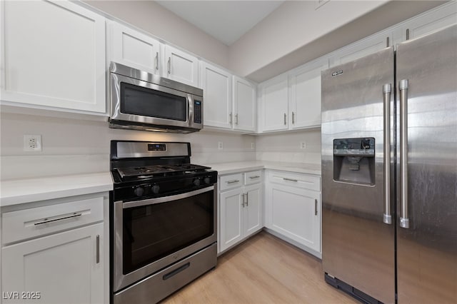 kitchen with stainless steel appliances, white cabinets, and light wood-type flooring