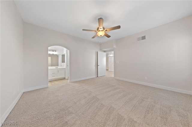 unfurnished bedroom with connected bathroom, light carpet, and ceiling fan