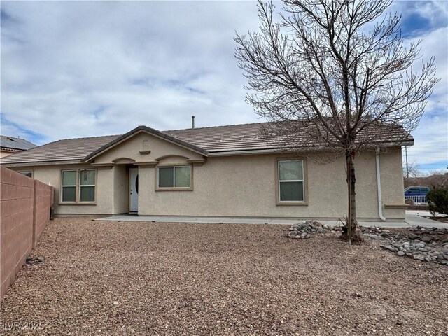 back of property with a tile roof, fence, and stucco siding