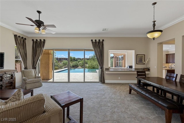 carpeted living room featuring ceiling fan, ornamental molding, and sink