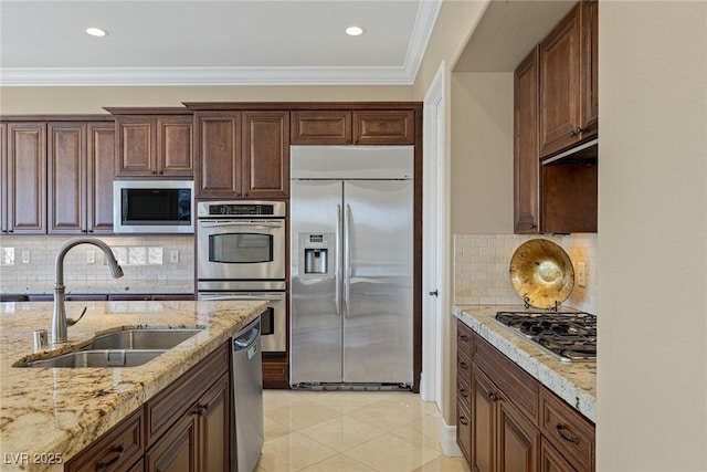 kitchen with light tile patterned flooring, sink, light stone counters, built in appliances, and ornamental molding