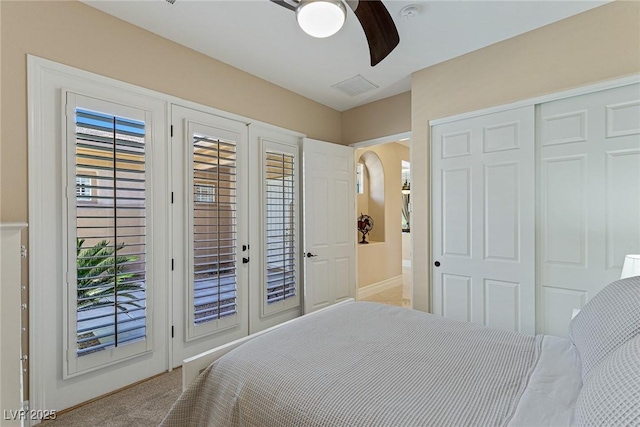 bedroom featuring a closet, access to outside, ceiling fan, light carpet, and french doors