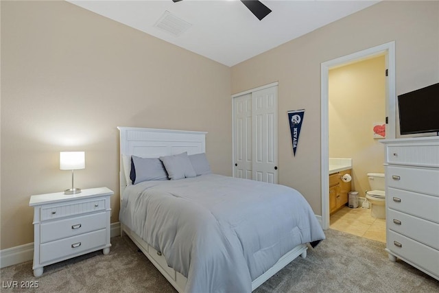 bedroom featuring ceiling fan, a closet, connected bathroom, and light carpet