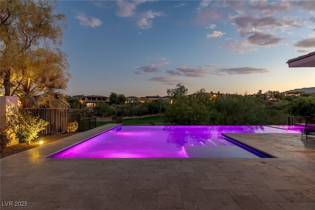 pool at dusk with a patio area