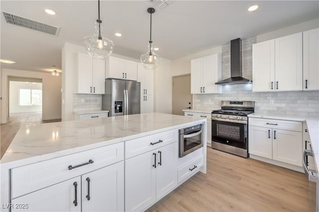 kitchen featuring white cabinetry, stainless steel appliances, and wall chimney exhaust hood