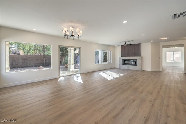 unfurnished living room with light wood-type flooring, recessed lighting, visible vents, and a glass covered fireplace