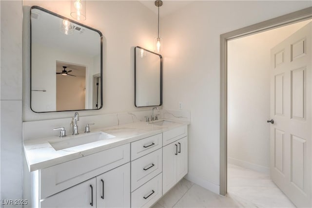 full bath with double vanity, marble finish floor, baseboards, and a sink