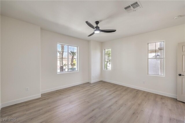 empty room with ceiling fan, light wood-style flooring, visible vents, and baseboards