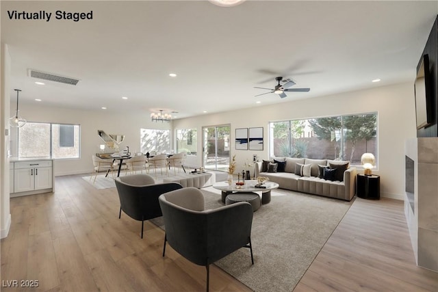 living room with light wood-type flooring, a fireplace, visible vents, and recessed lighting