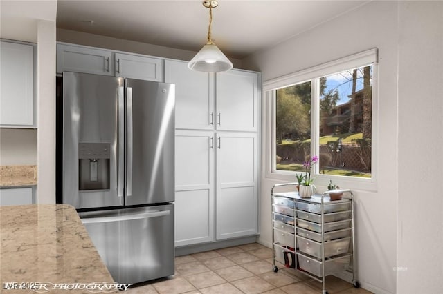 kitchen featuring hanging light fixtures, stainless steel refrigerator with ice dispenser, white cabinets, and light stone counters