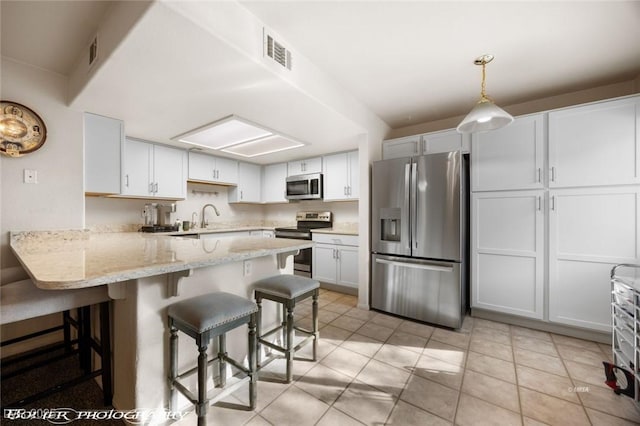 kitchen with hanging light fixtures, a kitchen breakfast bar, white cabinets, and appliances with stainless steel finishes