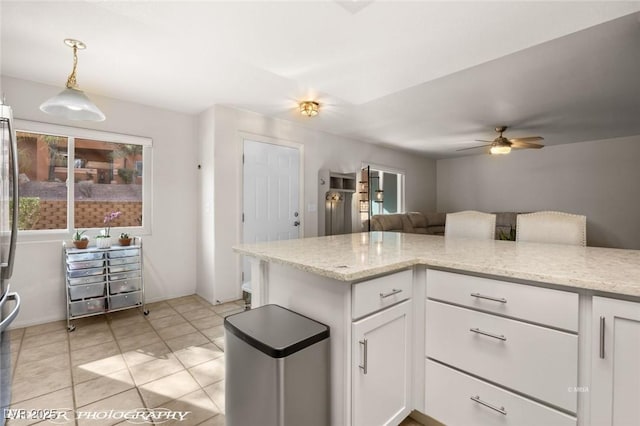 kitchen with ceiling fan, light stone countertops, hanging light fixtures, and white cabinets