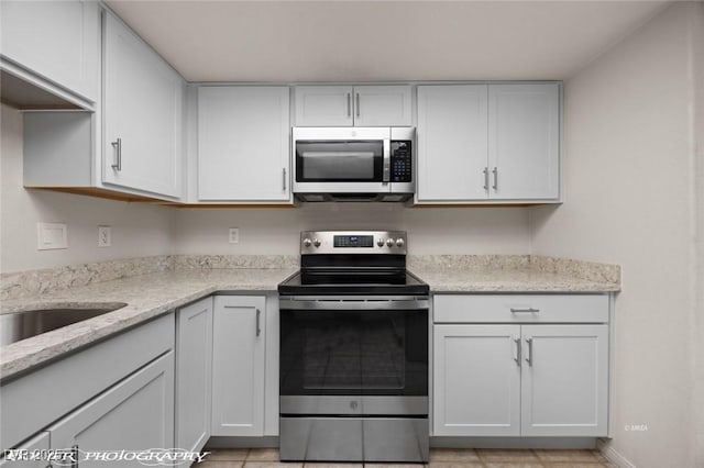 kitchen featuring white cabinetry, light stone countertops, and appliances with stainless steel finishes