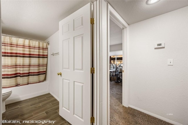 bathroom with toilet, shower / tub combo, and a textured ceiling