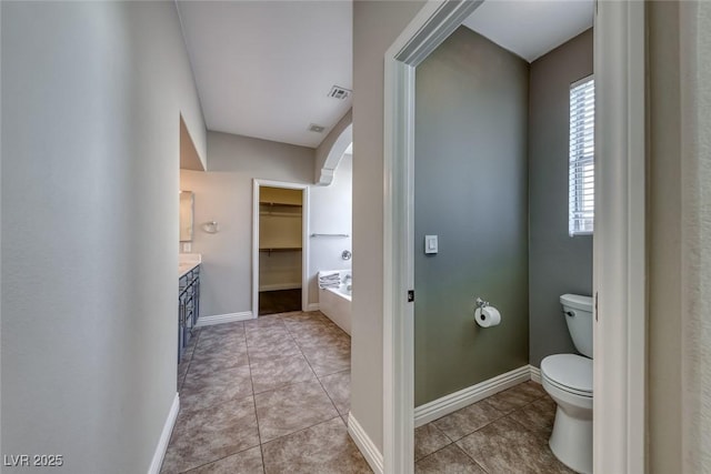 bathroom with tile patterned flooring, vanity, a bathing tub, and toilet