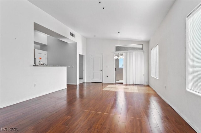 unfurnished living room with lofted ceiling, dark hardwood / wood-style floors, and a chandelier