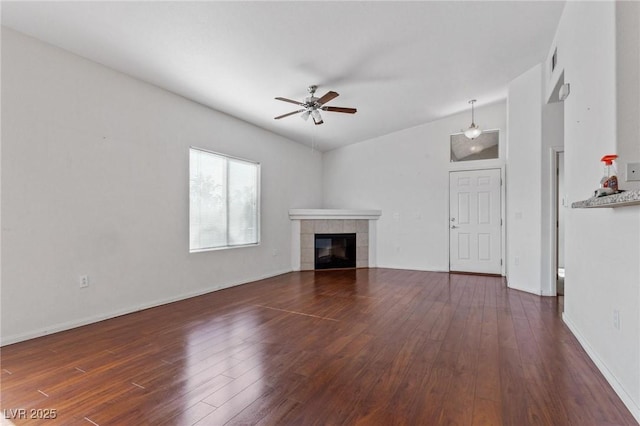 unfurnished living room with a tile fireplace, lofted ceiling, dark wood-type flooring, and ceiling fan