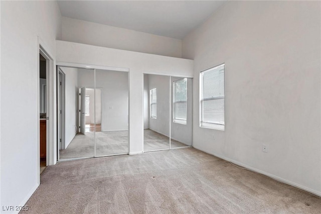 unfurnished bedroom with multiple closets and light colored carpet