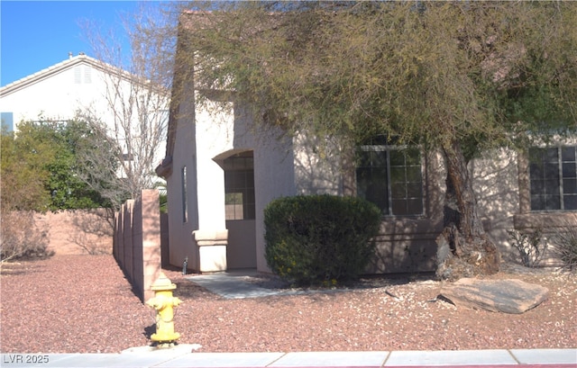 view of front facade featuring stucco siding and fence