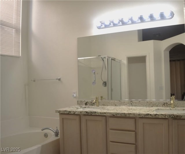 bathroom with double vanity, a sink, a garden tub, and a stall shower