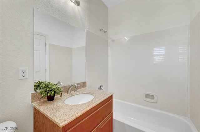 bathroom featuring a textured wall, shower / bathing tub combination, and vanity