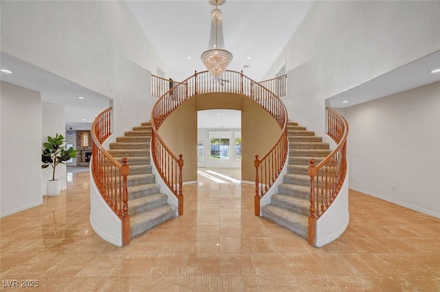 stairway with arched walkways, a notable chandelier, recessed lighting, a towering ceiling, and baseboards