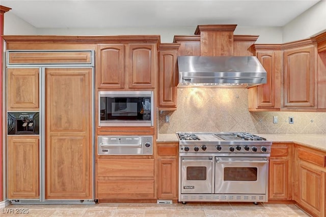 kitchen featuring wall chimney range hood, decorative backsplash, a warming drawer, and built in appliances