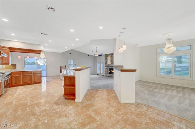 kitchen with light colored carpet, visible vents, open floor plan, vaulted ceiling, and decorative light fixtures